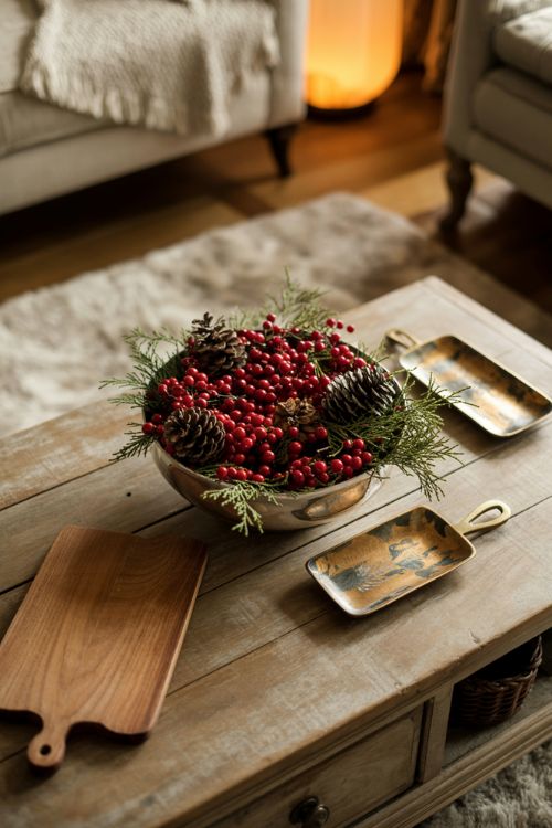Elegant coffee table decor with pinecones, cranberries, cedar sprigs, and metallic accents on wooden trays for a natural fall to winter transition.