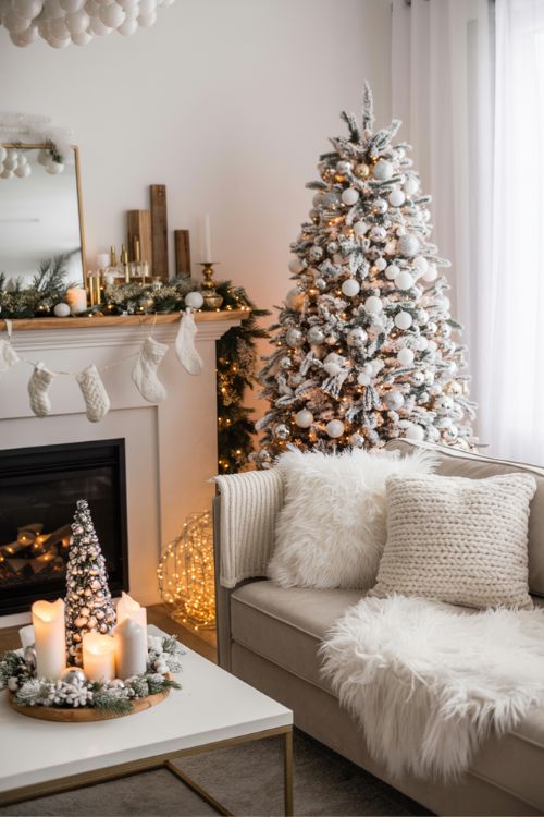 Cozy living room with a flocked Christmas tree, white faux fur throws, fairy lights, and silver and gold accents for an elegant white Christmas decor theme