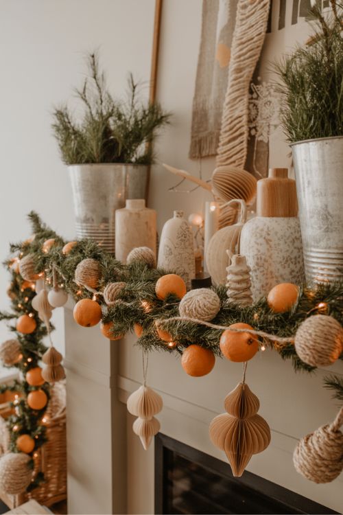 DIY neutral Christmas decorations with twine and dried orange garland, soft white lights, vintage vessels as planters, paper ornaments, creating a cozy, warm, and handcrafted holiday atmosphere.