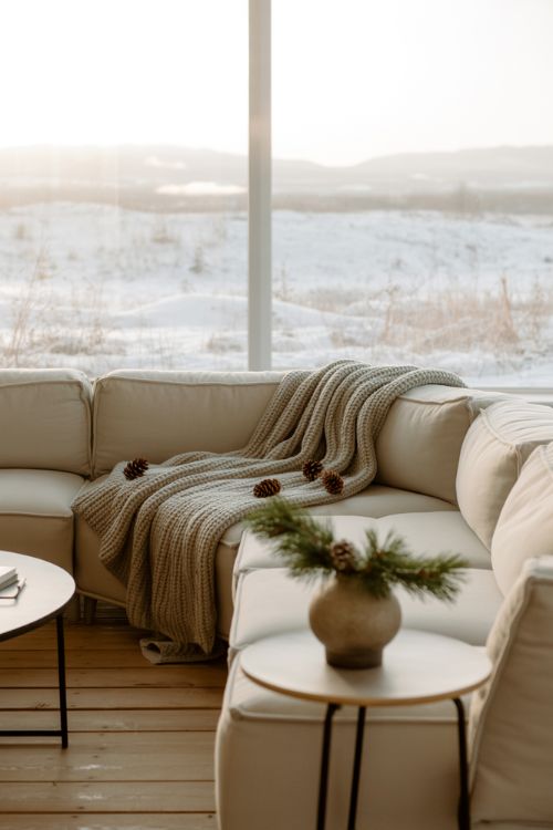 Minimalist winter living room with decluttered surfaces, neutral furniture, and a few cozy seasonal accents for a serene home.