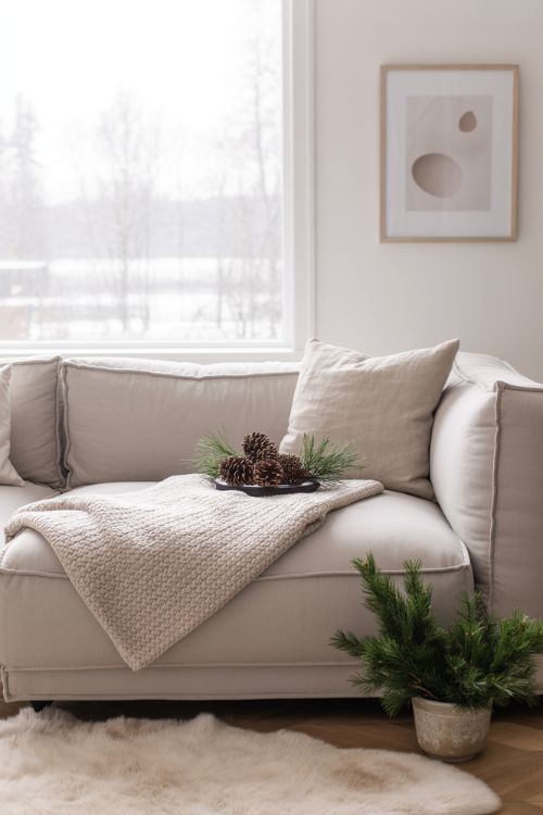 Minimalist winter living room with decluttered surfaces, neutral furniture, and a few cozy seasonal accents for a serene home.