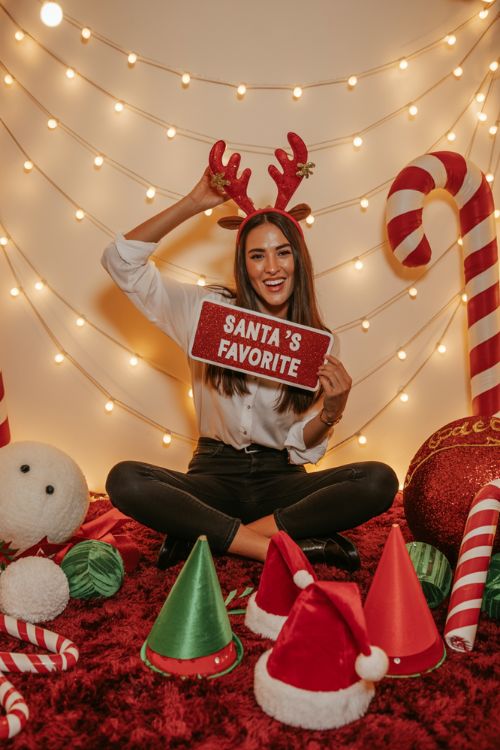Interactive Christmas party decor with photo booth props, gingerbread house station, festive dessert table, and cozy game areas with holiday trivia.