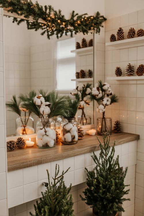 Rustic Christmas bathroom decor with cedar stems, mini pine trees, faux garland, glass jars, and pinecones.