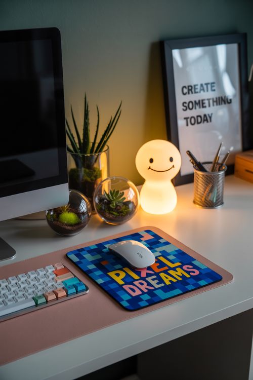 home office desk featuring artisan keycaps, custom mouse pad, decorative trays, DIY terrariums, and a resin lamp shaped like an anime character, creating a unique and inspiring workspace.