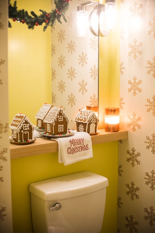 Christmas bathroom decor with mini gingerbread houses on a shelf, paired with a festive hand towel and scented candle.