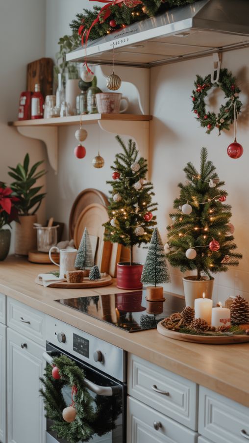 A cozy, festive kitchen featuring Christmas counter décor with miniature trees and ornaments. Small potted trees and bottlebrush trees are arranged on countertops and kitchen islands, decorated with tiny ornaments and soft LED lights. Additional mini ornaments hang from cabinet handles and light fixtures, adding vertical festive touches. Countertop vignettes display pinecones, candles, trays, and festive mugs, while wreaths hang on cabinet doors and garlands drape along shelves. The color palette is simple with classic red, white, and muted gold accents, complemented by natural greenery and seasonal plants like poinsettias. Soft natural light illuminates textures, creating a warm, stylish, and Instagram-worthy holiday kitchen scene.Keywords/Focus: Kitchen Counter Christmas Decor Ideas, mini Christmas trees, holiday kitchen ornaments