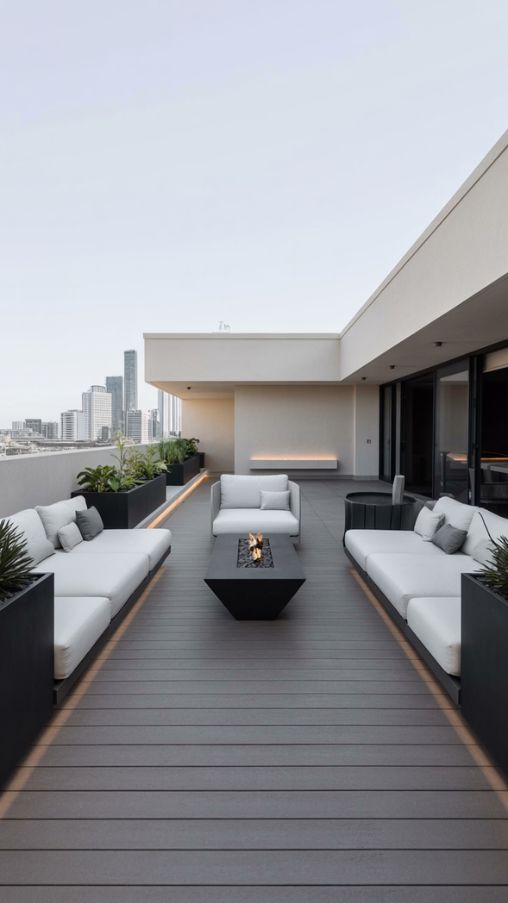 Modern minimalist rooftop terrace with white seating, black planters, and LED lighting creating a sleek, serene look