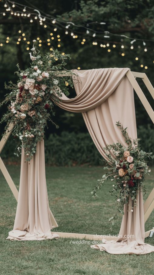 Wedding ceremony with a hexagon arch draped in flowers and greenery, soft flowing fabrics, and fairy lights
