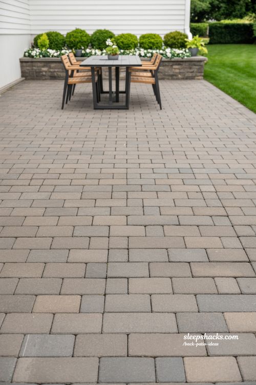 Elegant Grey Stone Paver Patio with Modern Outdoor Dining Set and Minimalist Landscaping