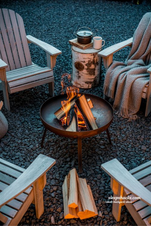 Small backyard fire pit ideas featuring a steel fire bowl and wooden chairs to create a cozy gathering space at night