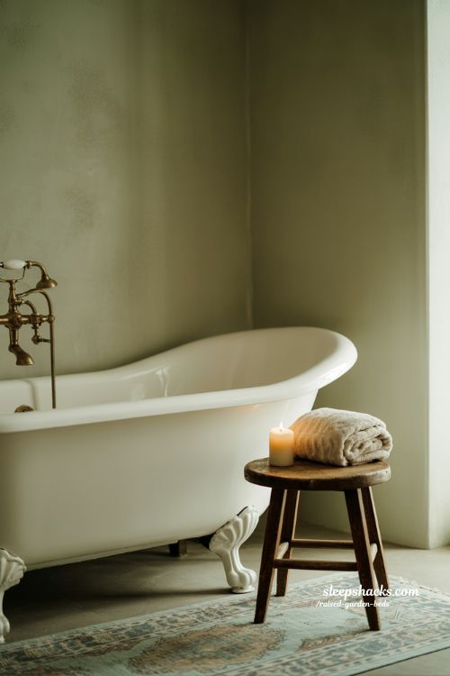 Vintage bathroom decor centered around a classic clawfoot tub and faded rug in sharp focus