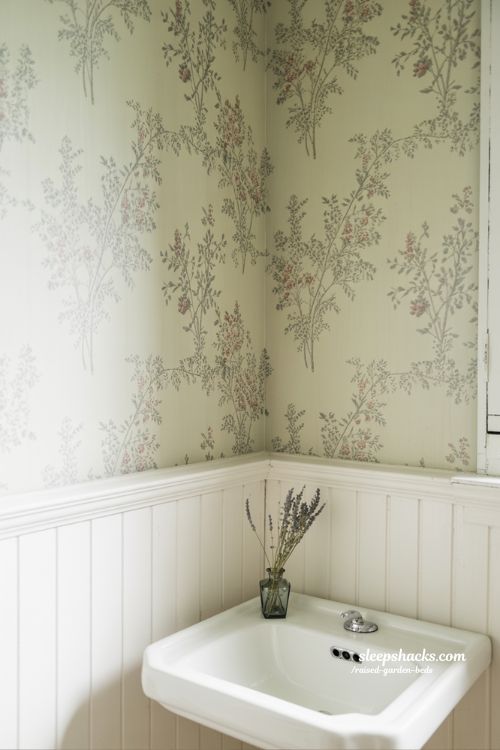 Vintage bathroom decor with floral botanical wallpaper and white wainscoting in sharp focus