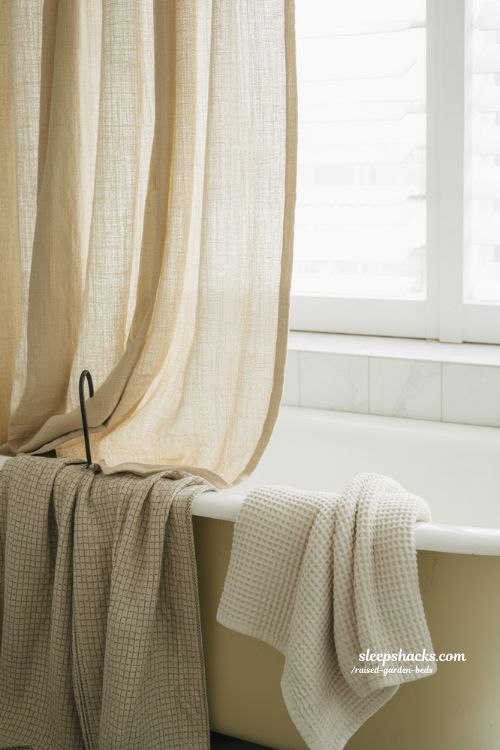 Vintage bathroom decor with linen curtains and woven rug in sharp focus