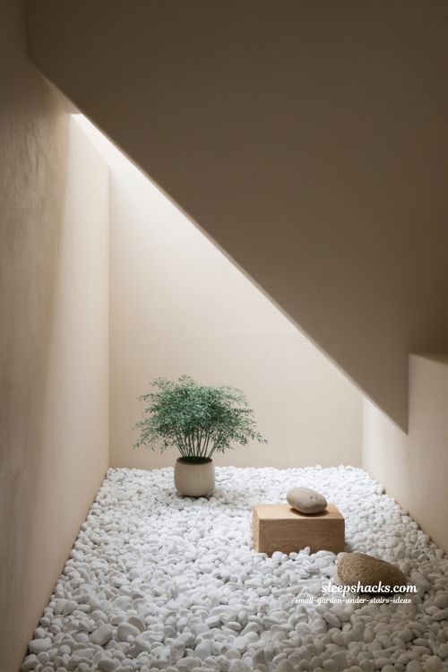 Minimal pebble garden under stairs with white stones and single plant decor 