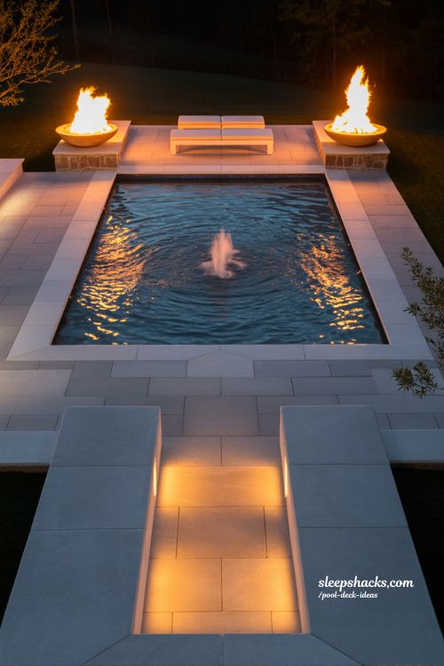 Paver pool deck with fire bowls and water feature luxury backyard night design 