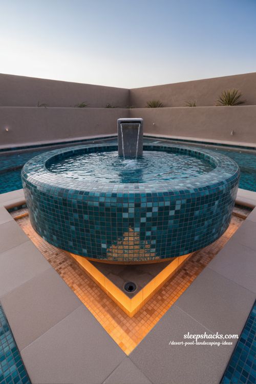 Raised glass tile spa centerpiece in desert pool design with waterfall spillover luxury backyard ideas