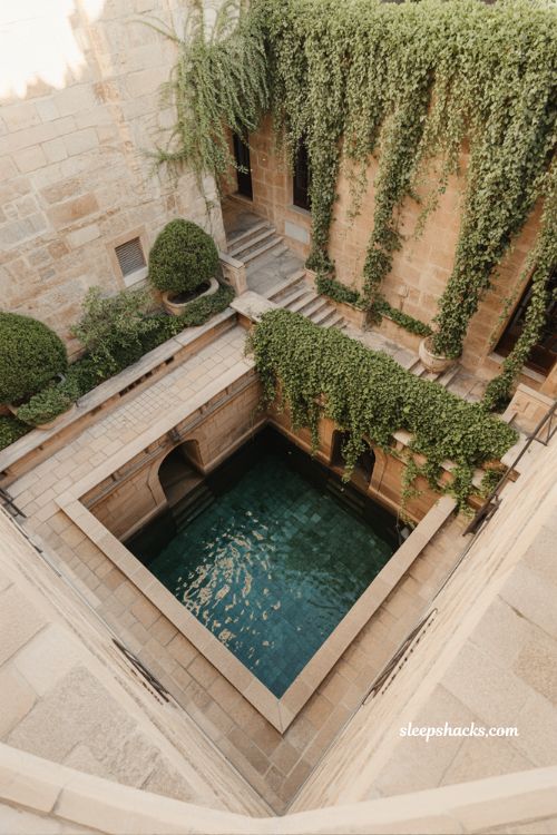 Recessed sunken courtyard pool with Mediterranean stone walls ivy climbing plants and intimate old world garden design