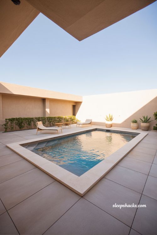 Small backyard rectangular pool with baja shelf minimalist resort style design neutral landscaping and clean modern outdoor living space styling