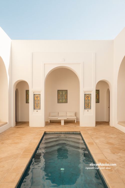 Spanish style pool ideas with arched white stucco cabana and tile courtyard design