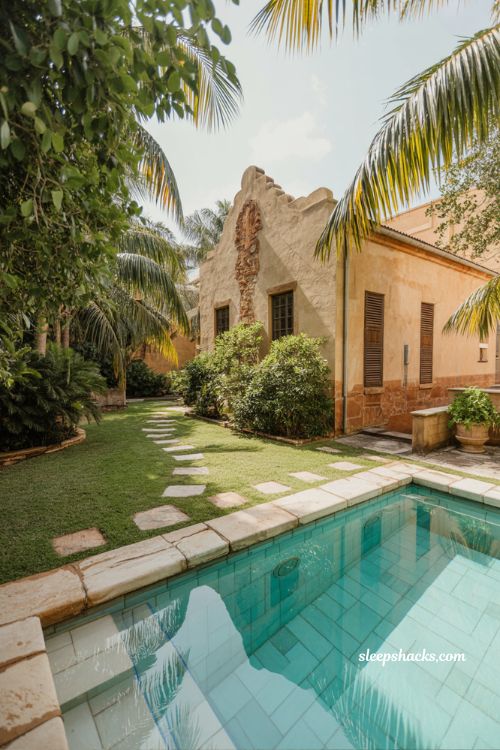 Tropical courtyard pool with vintage heritage home design limestone coping palm trees and lush lawn edge garden aesthetic