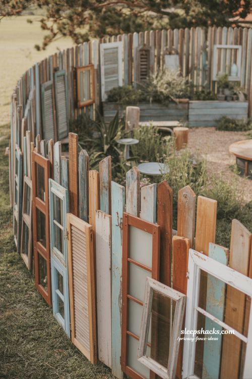 diy reclaimed wood privacy fence ideas with salvaged windows and shutters for a bohemian backyard design