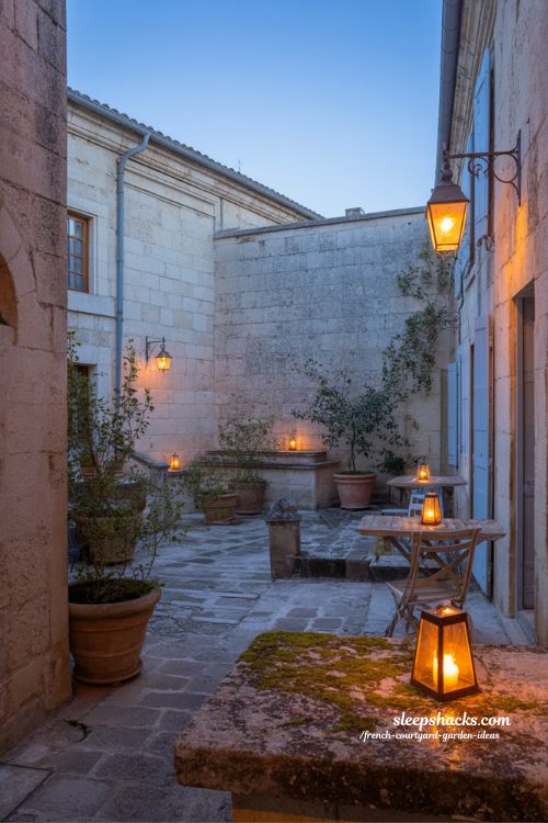 french courtyard garden evening lighting with lanterns creating warm shadows and intimate nighttime atmosphere