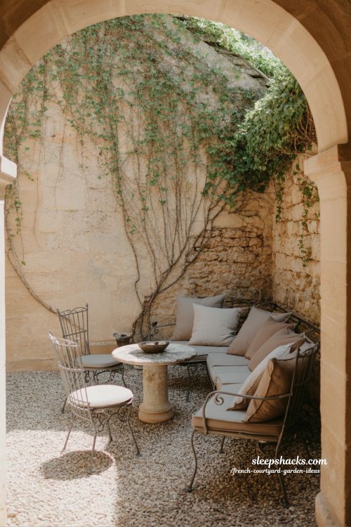 french courtyard garden seating area with rustic chairs and stone table creating calm outdoor living space