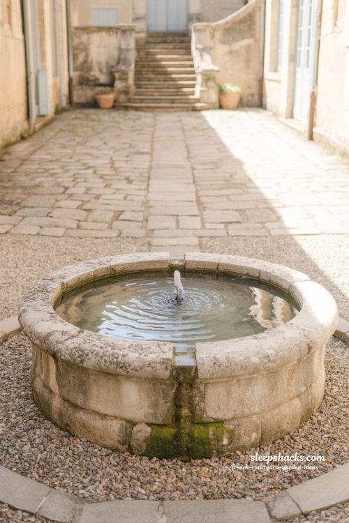 french courtyard garden stone fountain creating calm rustic atmosphere with aged stone and natural gravel setting