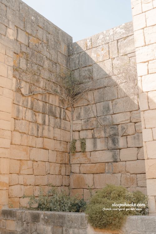 french courtyard garden stone walls with aged texture moss and timeless rustic architectural character