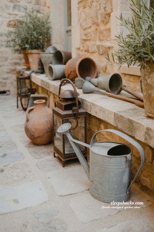 french courtyard garden with vintage watering can lantern and rustic objects adding personality and story
