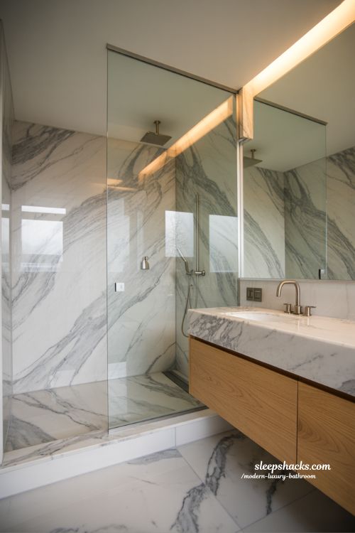 marble focused modern luxury bathroom with wood accents warm lighting and elegant spa inspired interior design 