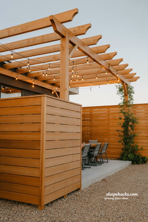 pergola topped privacy fence ideas for a small backyard outdoor entertainment space with string lights and seating