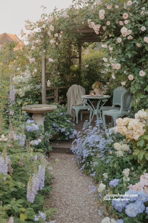 romantic french cottage garden dream backyard with winding gravel path spilling pastel flowers and cozy seating corner