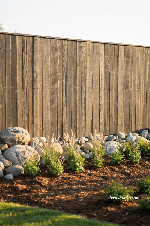 Backyard mulch ideas with layered rock beds and wood fence landscaping design