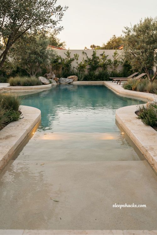 Beach entry pool design with natural sloping shoreline and stone landscape