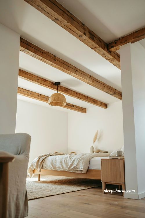 Beach house bedroom with exposed wood beams white walls coastal rustic ceiling design warm natural wood architectural cozy interior