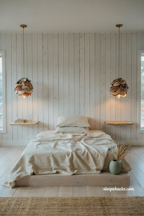 Beach house bedroom with shell pendant lights above nightstands warm coastal minimalist lighting organic woven decor floating bedside style
