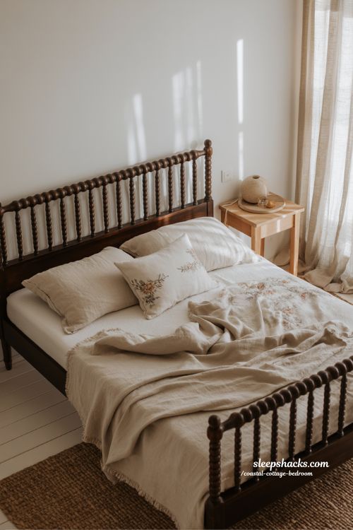 Coastal cottage bedroom with dark spindle bed frame white linen bedding and vintage charm