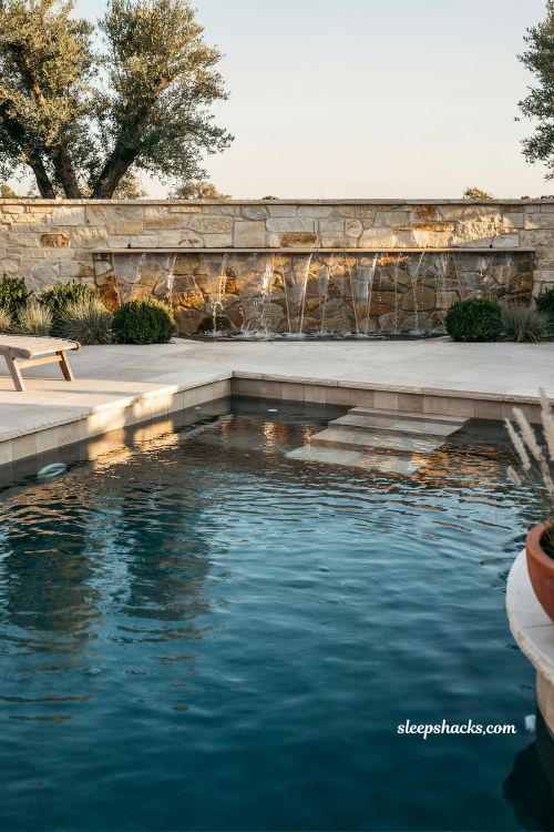 Gunite pool with cascade waterfall modern backyard luxury design raised bond beam water feature centerpiece elegant outdoor resort style