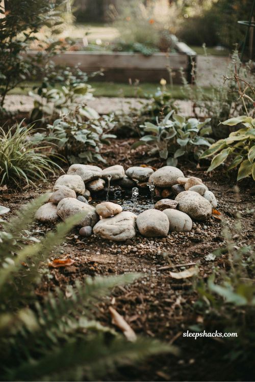 Half buried bucket fountain river rock solar water feature hidden garden bubbling water idea