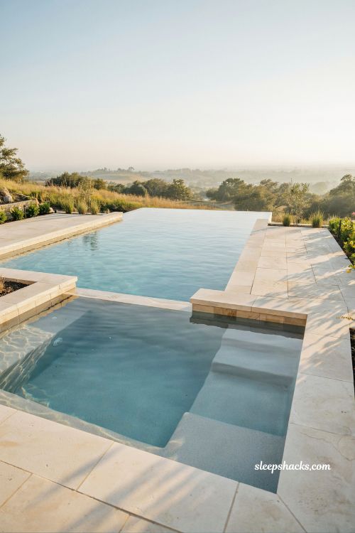 Infinity edge pool overlooking landscape modern luxury backyard design at golden hour with vanishing edge illusion and minimalist stone deck