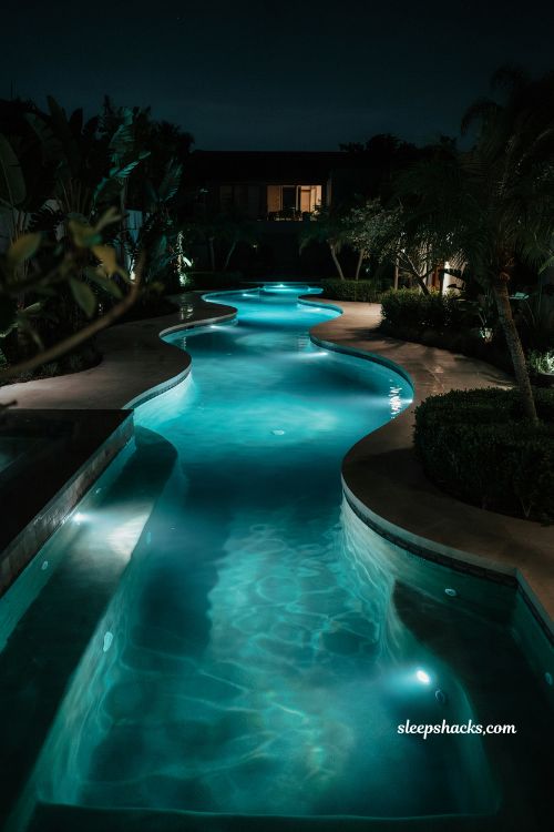 Lazy river at night with underwater LED lighting glowing backyard resort pool design ideas