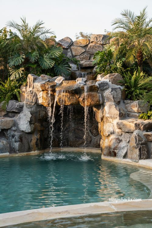 Luxury backyard pool with built-in grotto and waterfall feature surrounded by natural stone creating a dramatic resort-style outdoor swimming experience