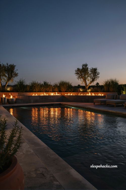 Luxury backyard pool with fire pit and fire features creating dramatic evening outdoor living space with water and fire contrast in modern resort-style design
