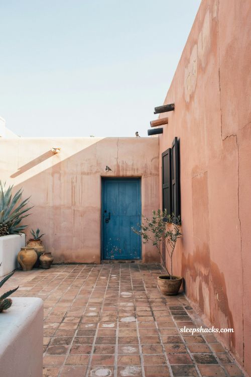Mexican hacienda patio ideas with terracotta adobe walls warm sun baked courtyard architecture rustic textured plaster exterior design cobalt accent door