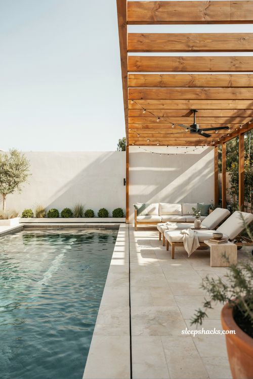Modern backyard pool with pergola shade structure and outdoor seating area creating a stylish shaded relaxation space beside a contemporary swimming pool