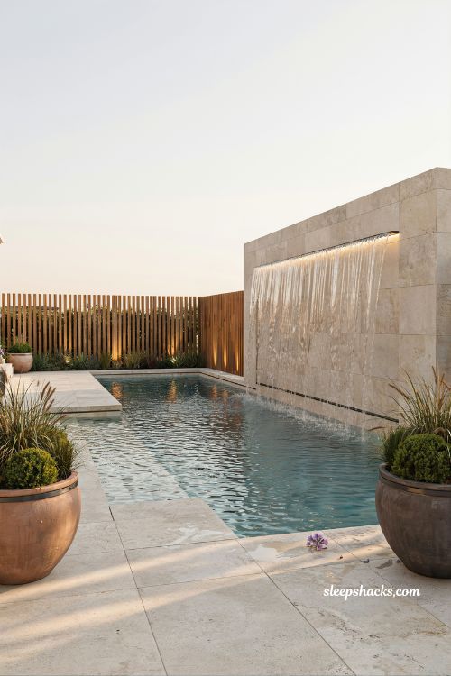 Modern pool design with sheer descent waterfall and LED lit architectural water feature