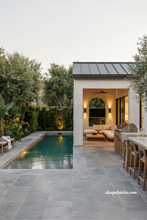 Pool house with outdoor kitchen and entertainment space beside modern pool