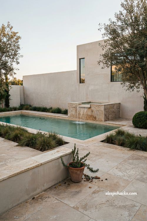Raised spa outside rectangular pool with waterfall spillover design idea