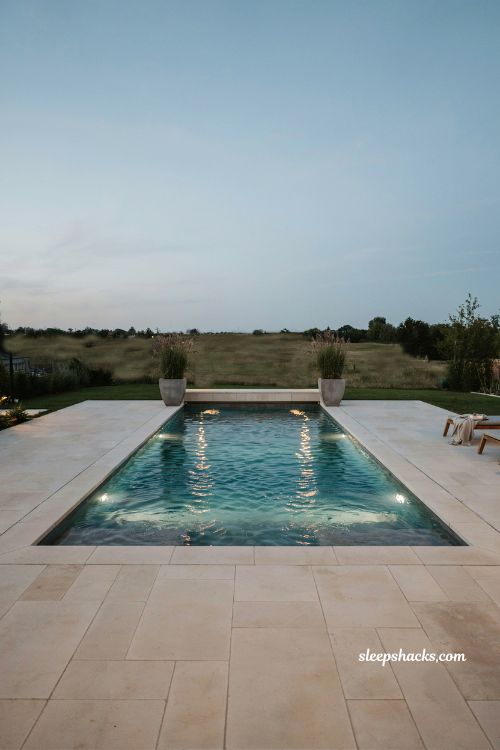 Rectangular pool with color changing LED lights under sun shelf at night design idea